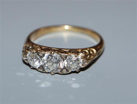 A diamond three-stone ring, claw-set in yellow metal with scrolled mount, size M.